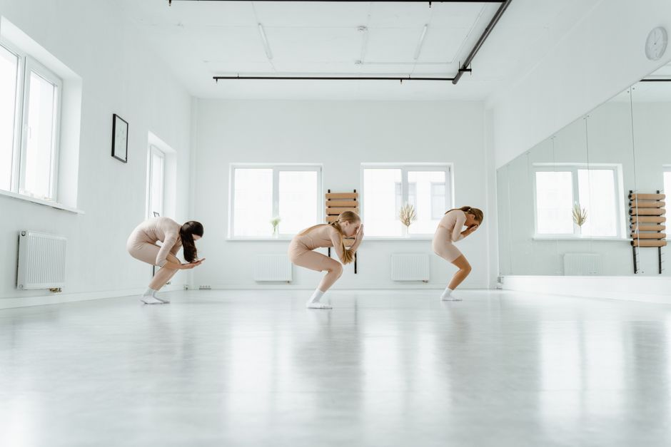 Three contemporary dancers performing in a bright, spacious dance studio.